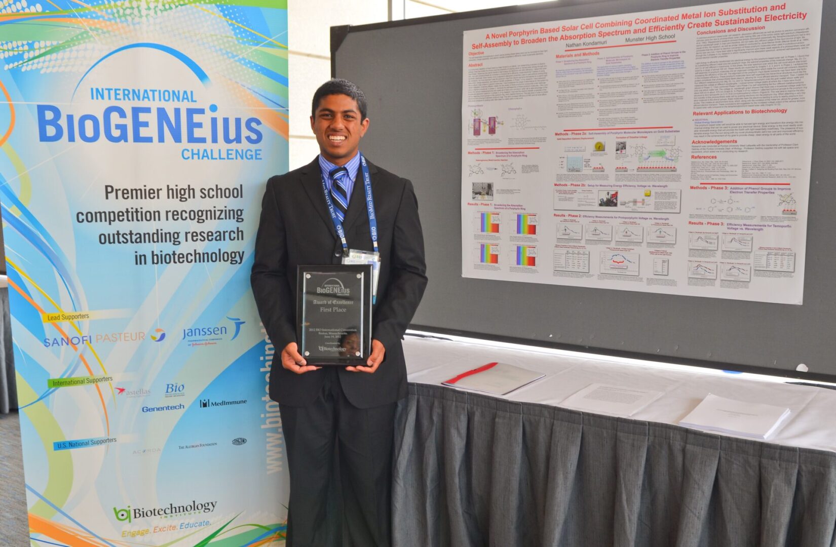 Young man in formal attire holding an award plaque at a conference.