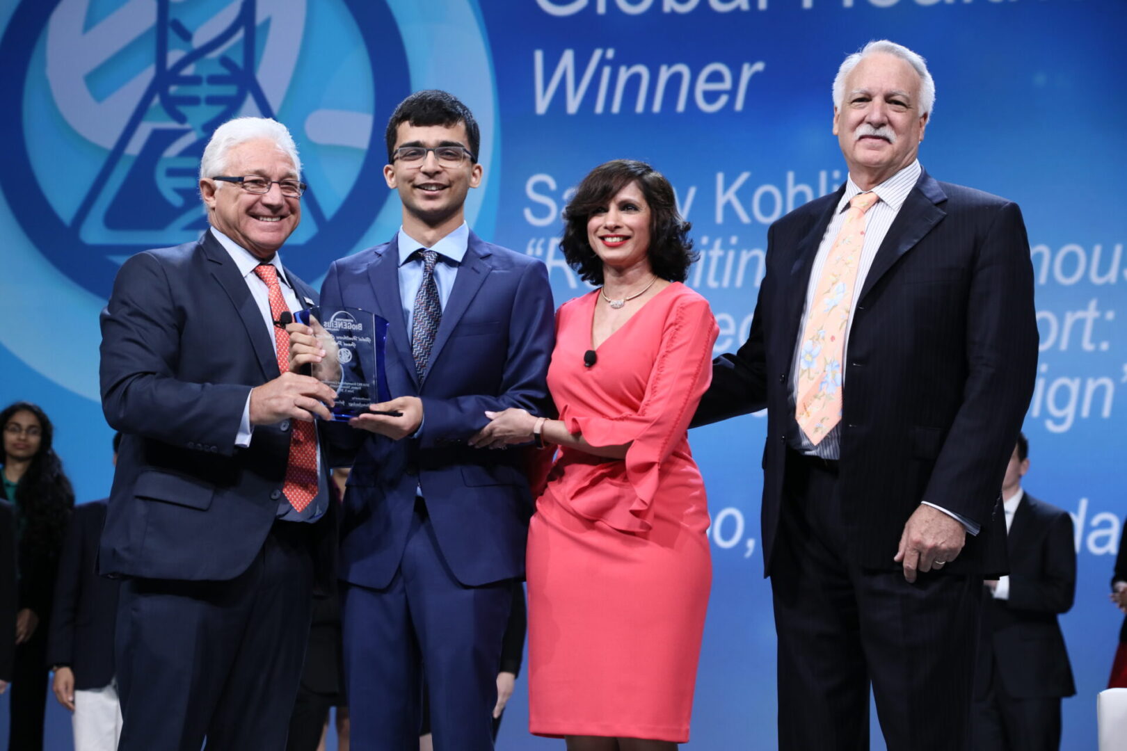 Four people posing with awards at a formal event.